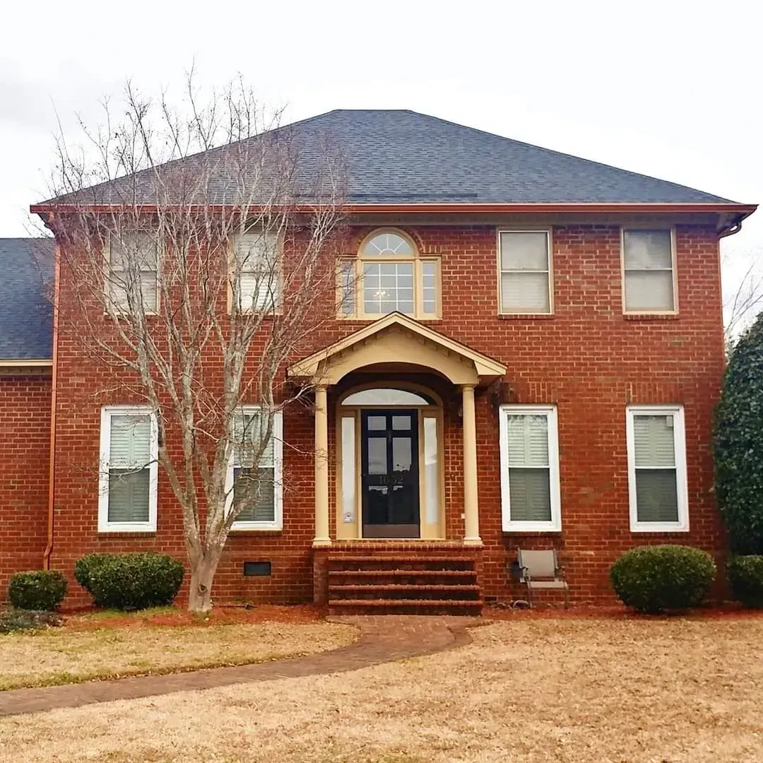 A large red brick house with a black door and a porch.