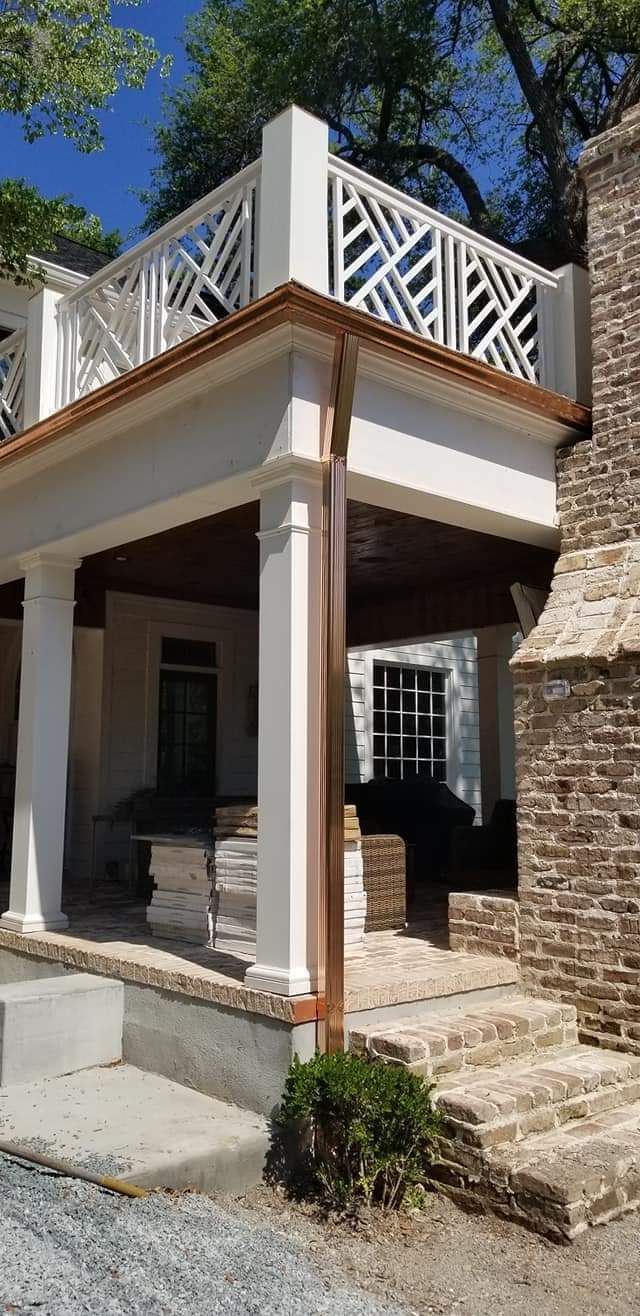 A house with a balcony and a copper gutter on the side of it.
