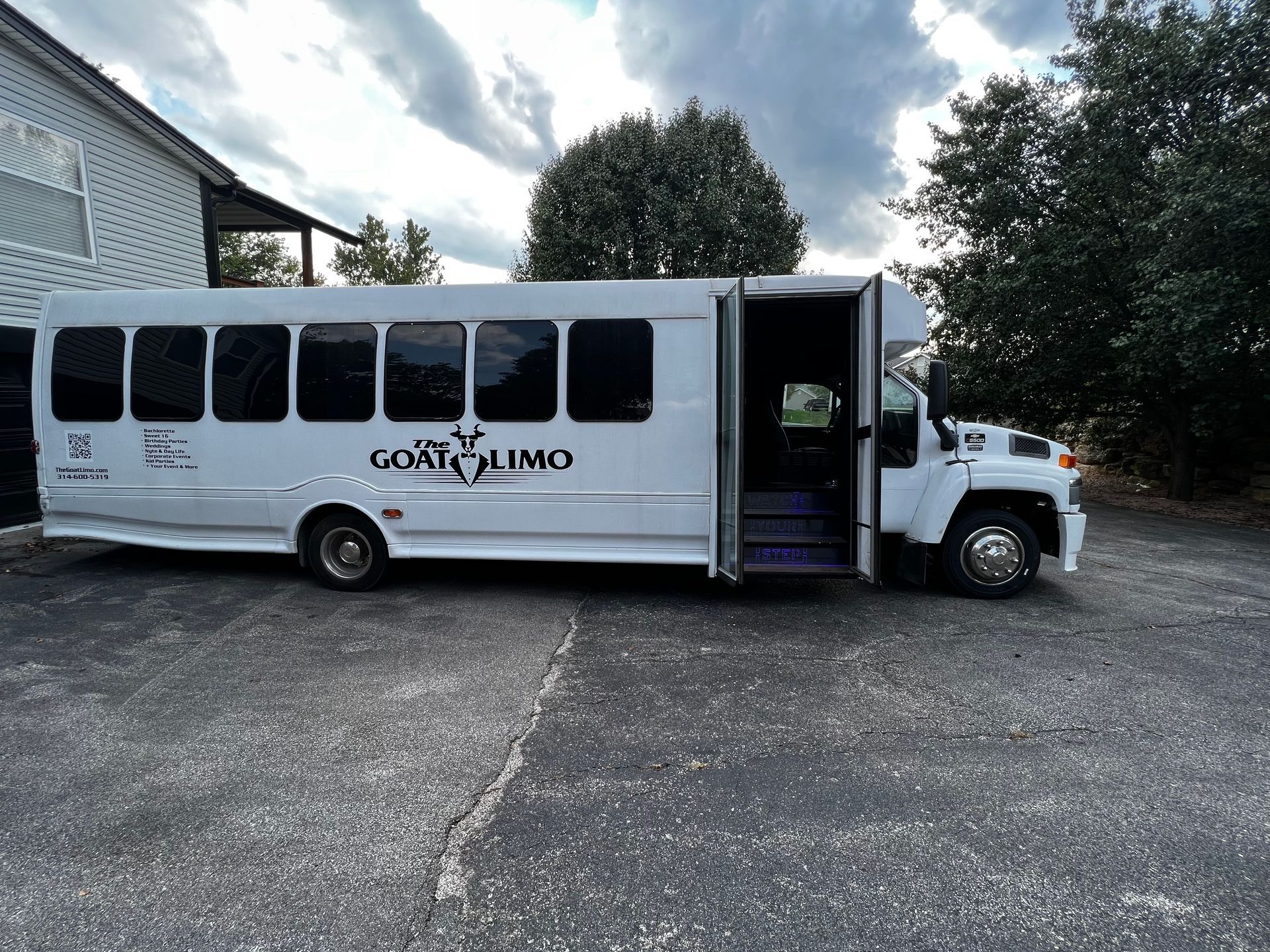 A white limo bus is parked in a parking lot