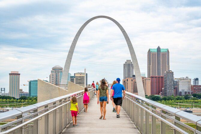 A group of people are walking across a bridge in front of a city skyline.