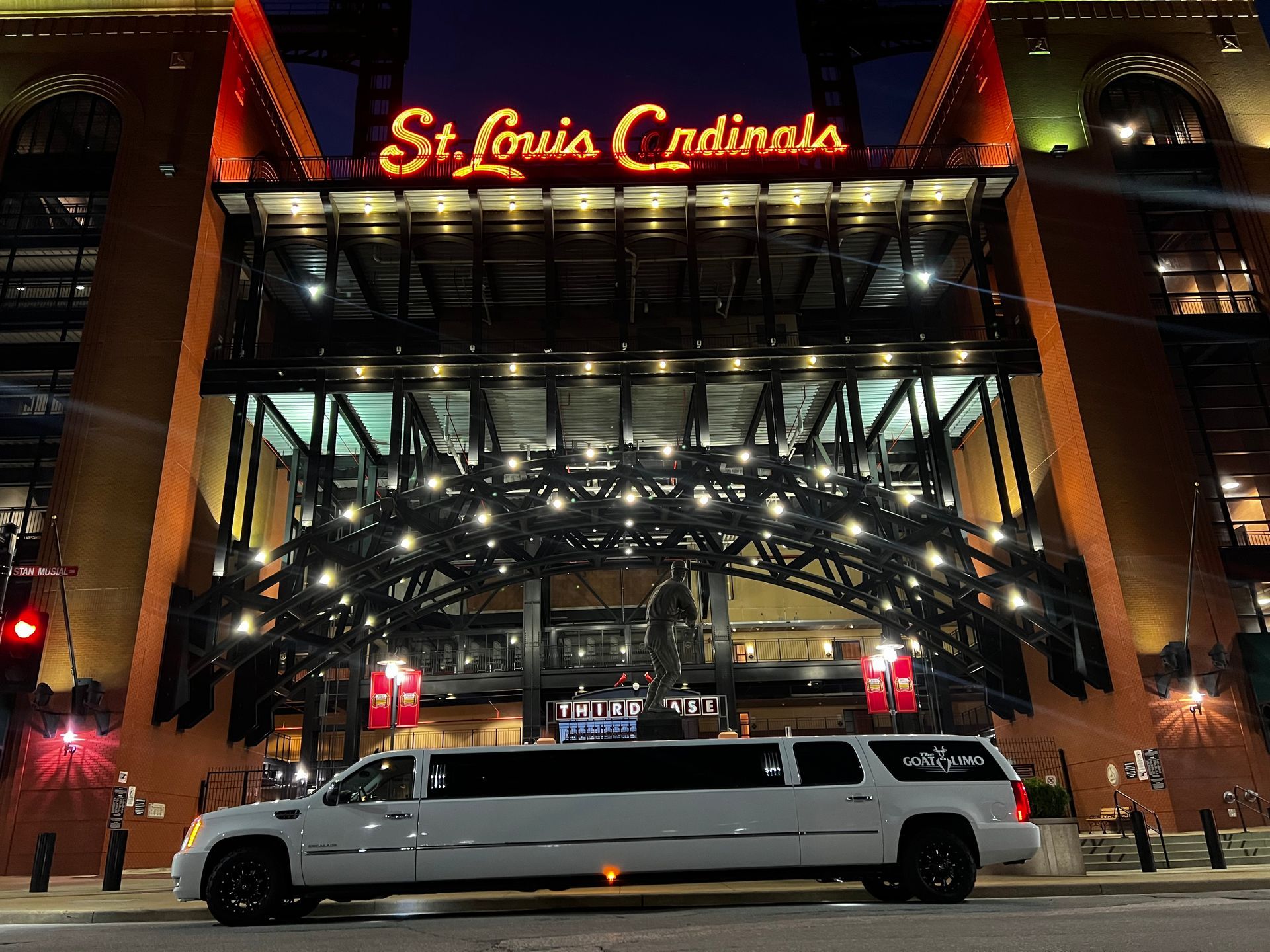A white limousine is parked in front of the st. louis cardinals stadium.