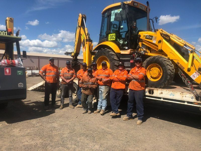 Group of Men Standing Beside Flatbed Truck Loaded With Heavy Machinery — Verification of Competency Newcastle