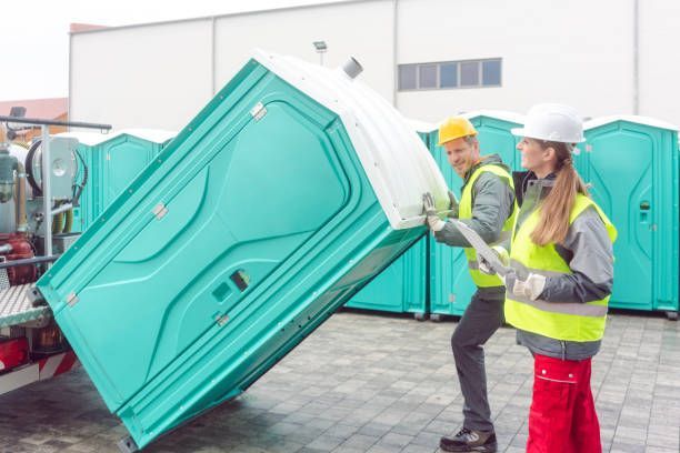 Mobile Toilet Rental—Workers Handling Units for Event Setup and Sanitation Services.