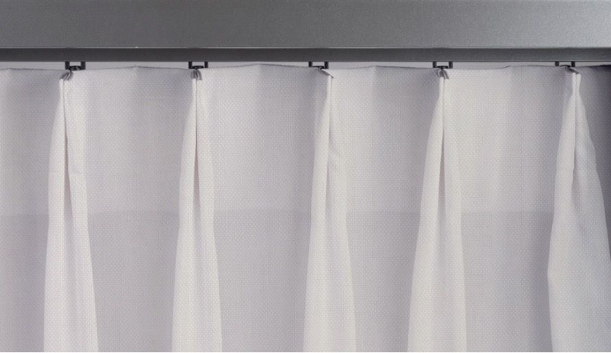 White curtains hanging from a gray rod with evenly spaced pleats.