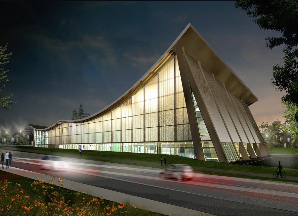 A large building with a curved roof is lit up at night