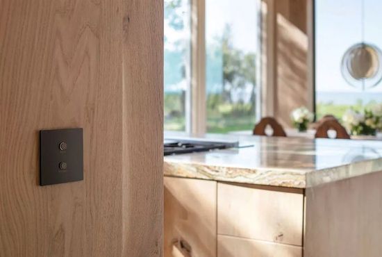 A kitchen with wooden cabinets and a black light switch on the wall.