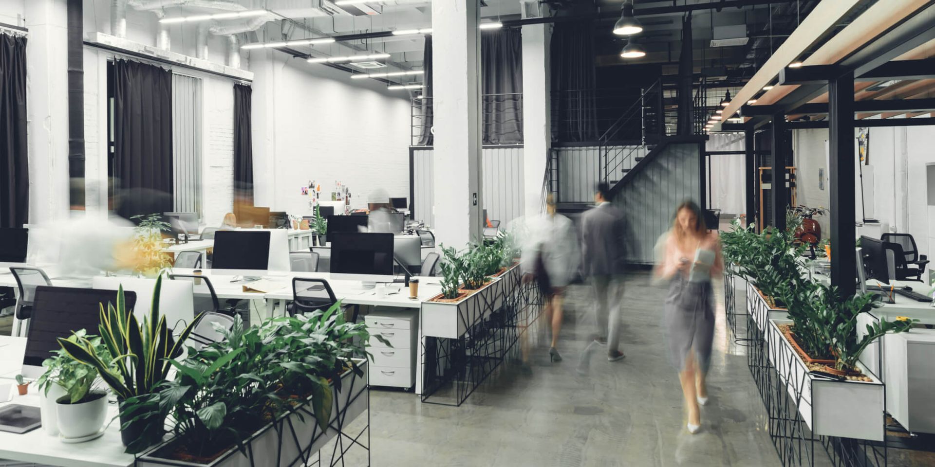 A blurry picture of a modern office with people walking through it.