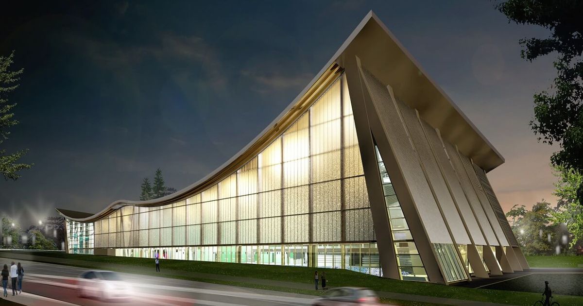 Modern building with sloped roof and glass windows, illuminated at night.