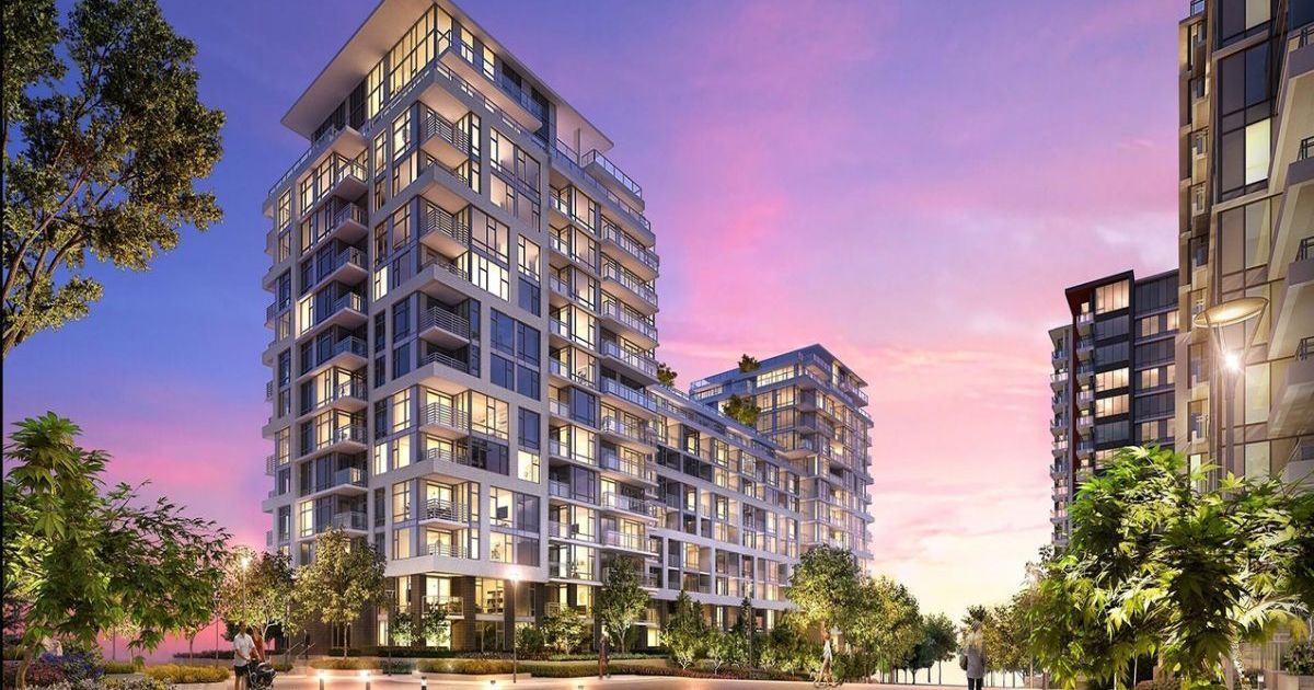 Modern apartment buildings at dusk with balconies and illuminated windows.