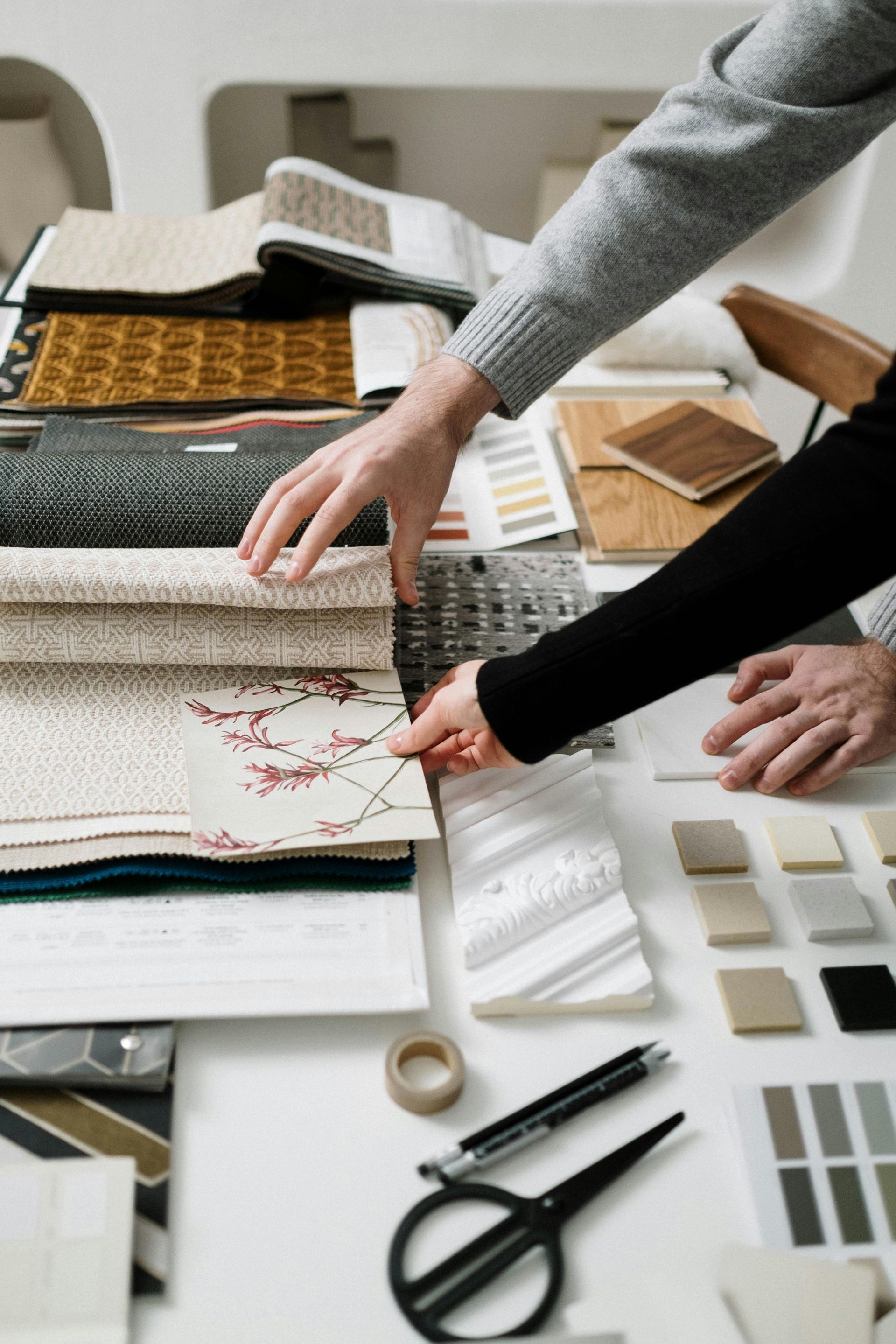 A couple of people are sitting at a table looking at fabrics.