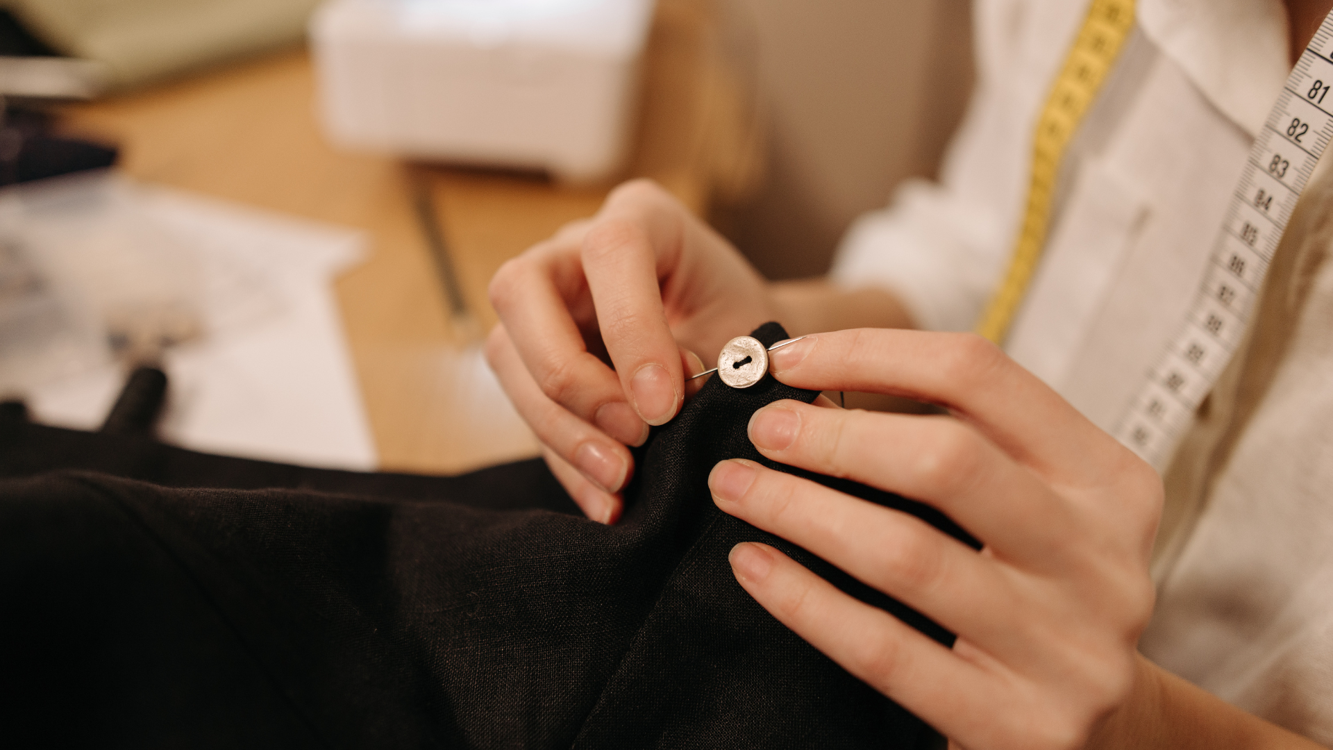 A person is sewing a button on a piece of fabric.
