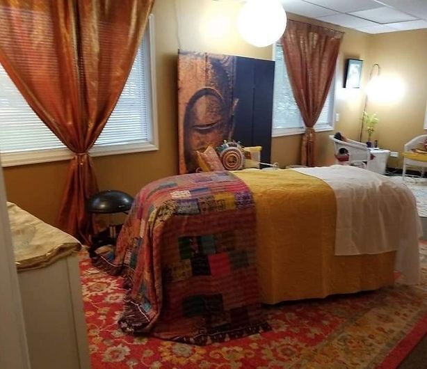 Massage room with bed, art, and warm colors.
