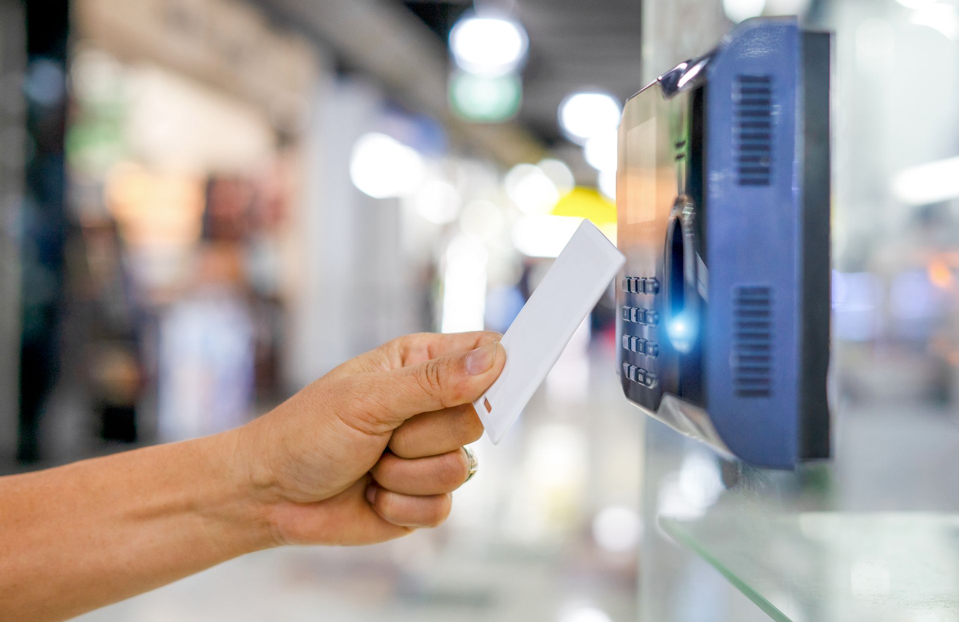 Close-up of a hand holding an access card near a security reader.
