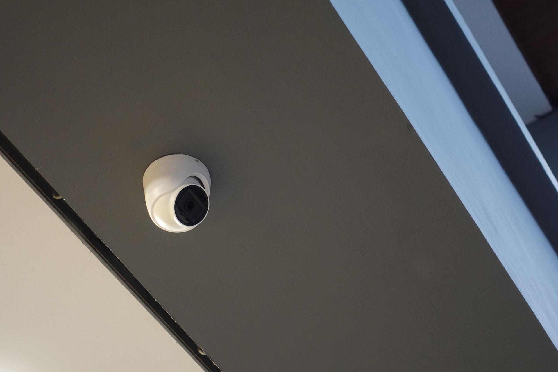 Security system installer mounts CCTV cameras on ceiling for indoor surveillance and monitoring.