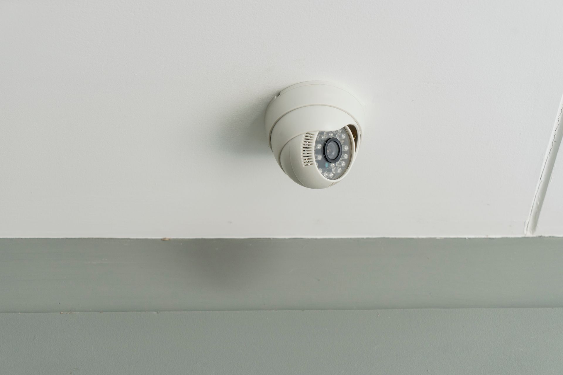 Security system installer sets up ceiling-mounted CCTV camera for indoor safety and surveillance.
