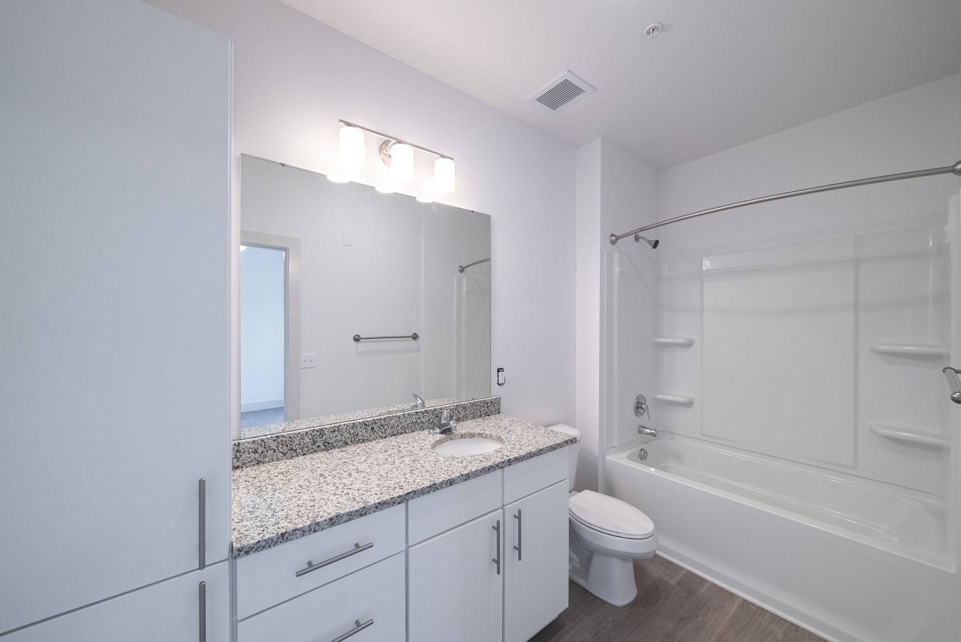 White bathroom with vanity, granite countertop, toilet, and bathtub with a shower.