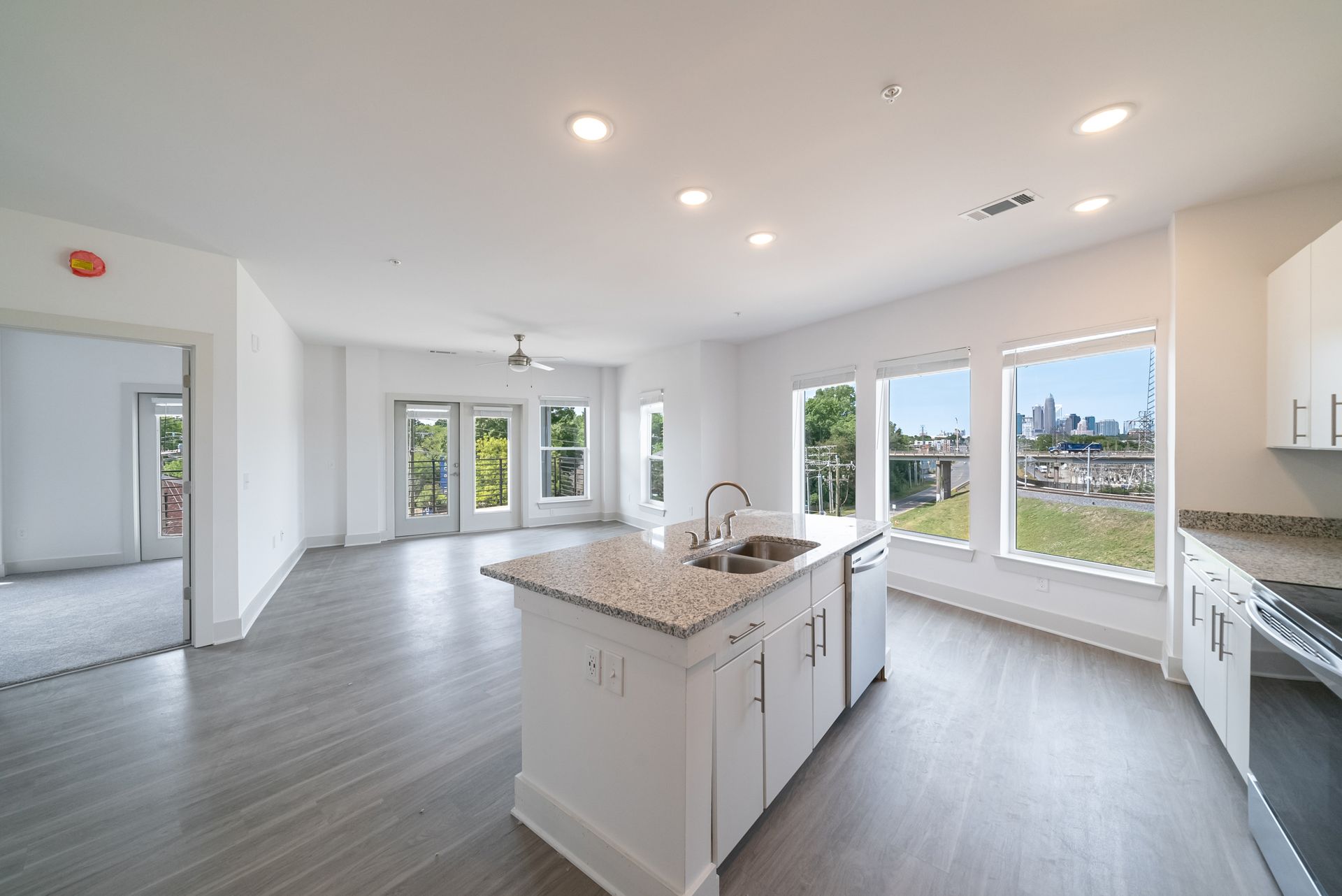 Open-concept apartment with kitchen island and large windows overlooking a city view.