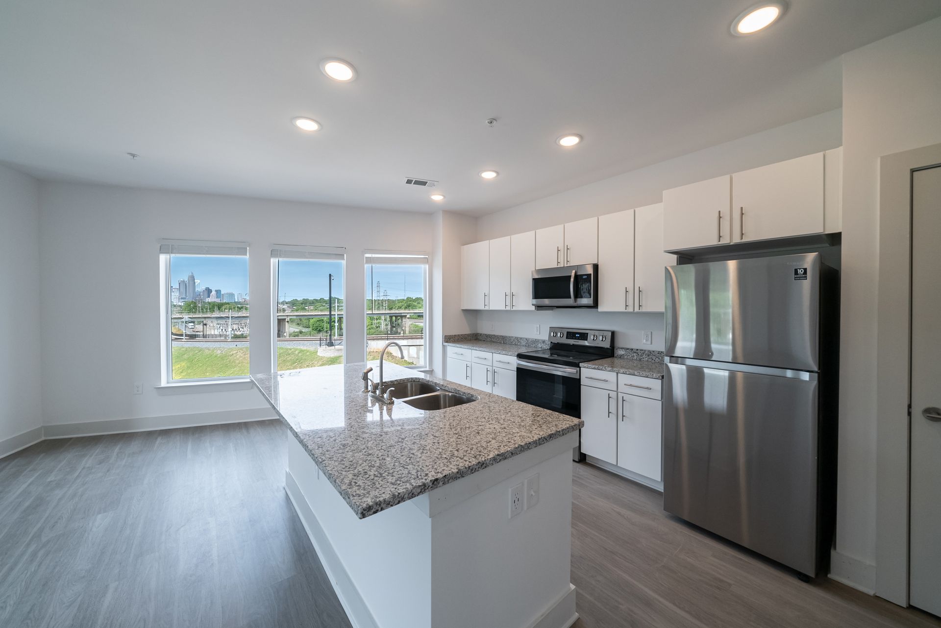 Bright, modern kitchen with white cabinets, stainless steel appliances, and a granite island.