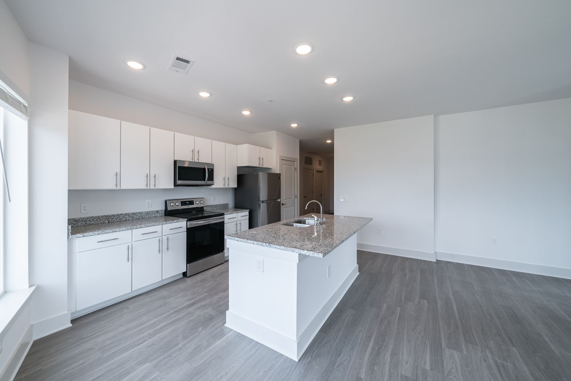 Modern kitchen with white cabinets, gray countertops, and stainless steel appliances.