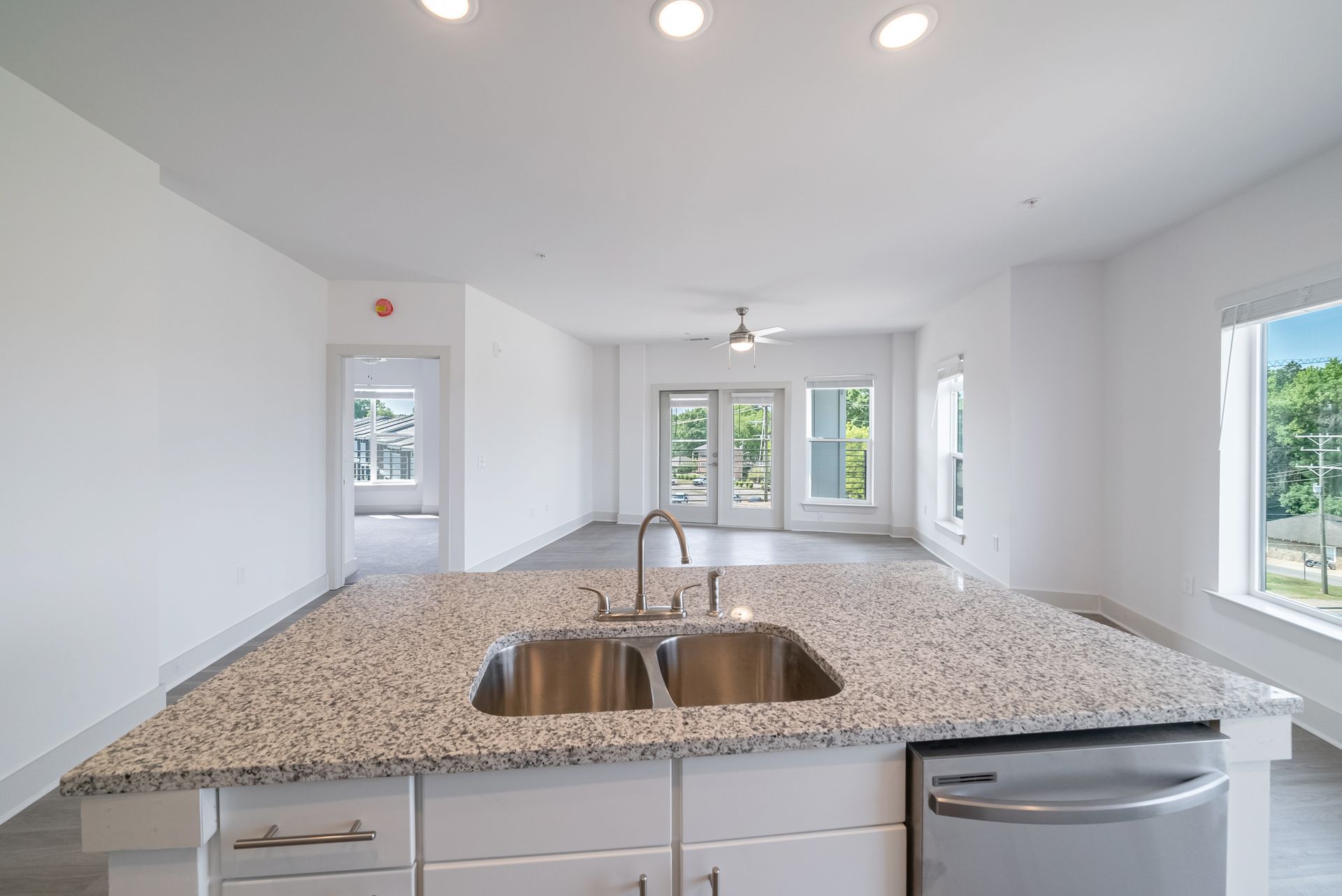 Kitchen island with granite countertop and stainless steel sink, overlooking a bright, open living space.