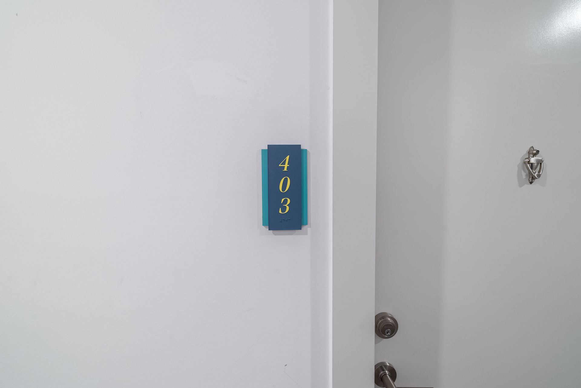 White door with number 403 on a blue sign. Another door is visible with a knob and keyhole.