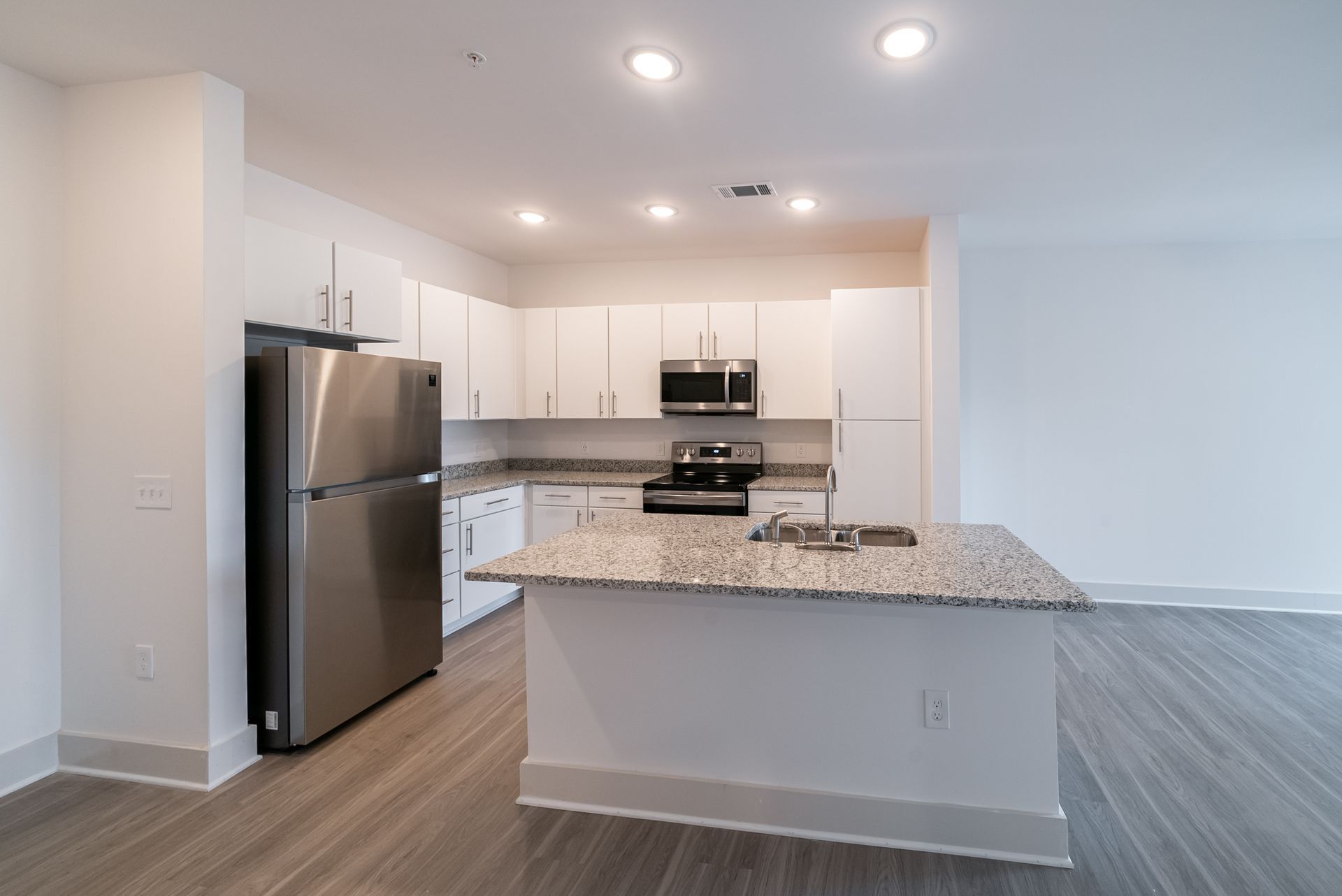 Modern kitchen with stainless steel appliances, white cabinets, and granite countertops.