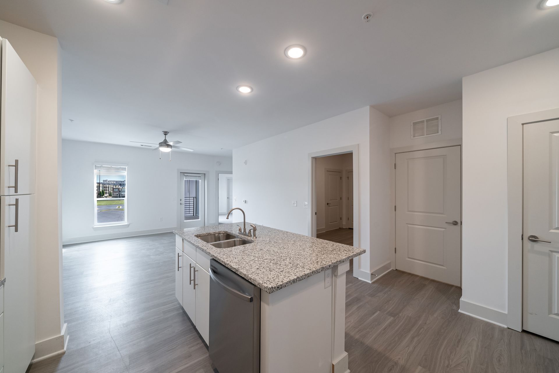 Modern, bright kitchen with island, granite countertop, and stainless steel appliances.