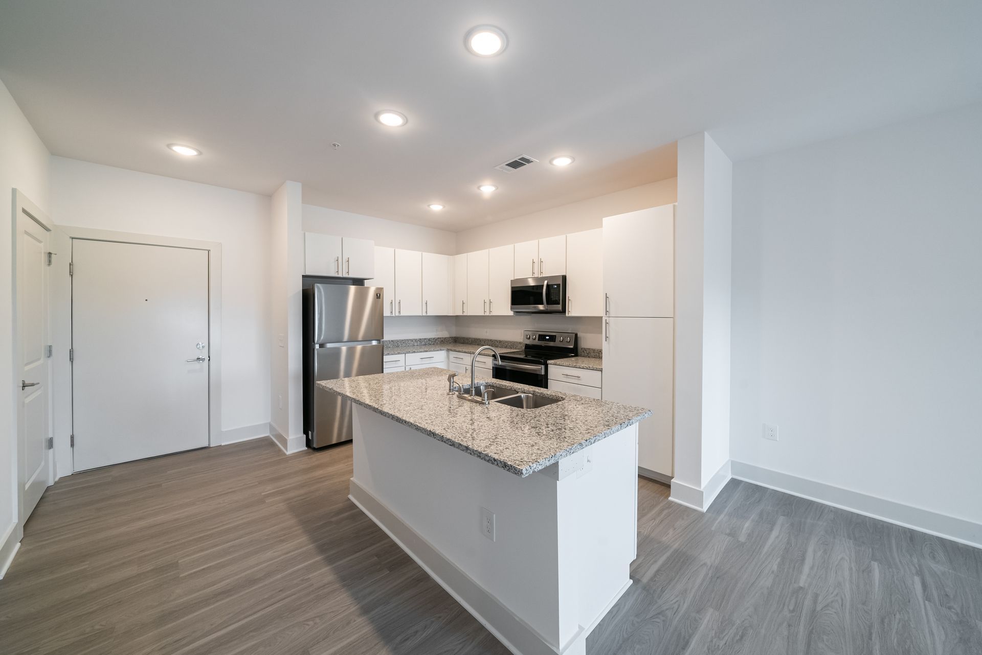 Modern kitchen with white cabinets, stainless steel appliances, and granite island.