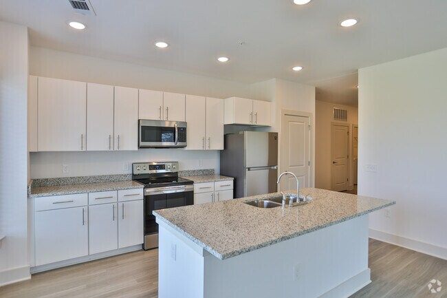 Modern kitchen with white cabinets, stainless steel appliances, granite countertops, and an island.
