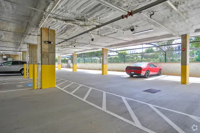 Parking garage with yellow columns and a red car parked on the right.