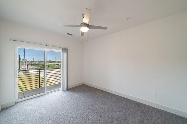 Empty white bedroom with gray carpet and a sliding door to a balcony.