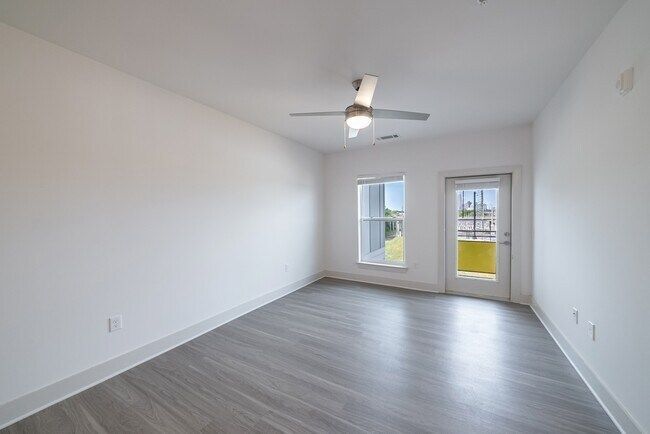 Empty room with gray flooring, white walls, a door, and a window.
