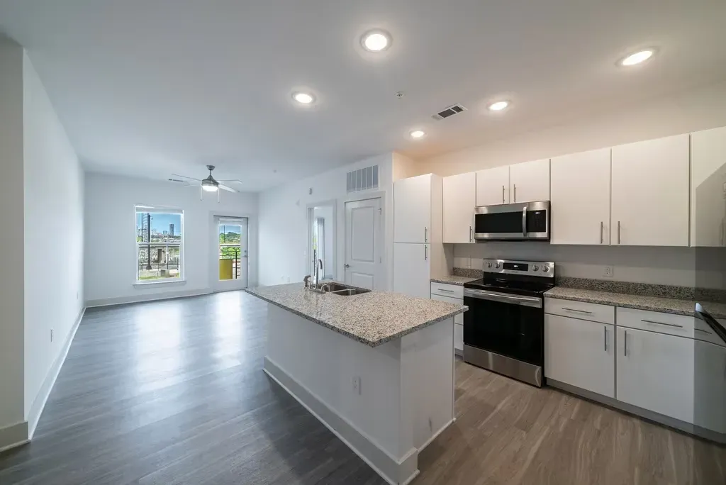 Modern kitchen with white cabinets, gray island, and stainless steel appliances.