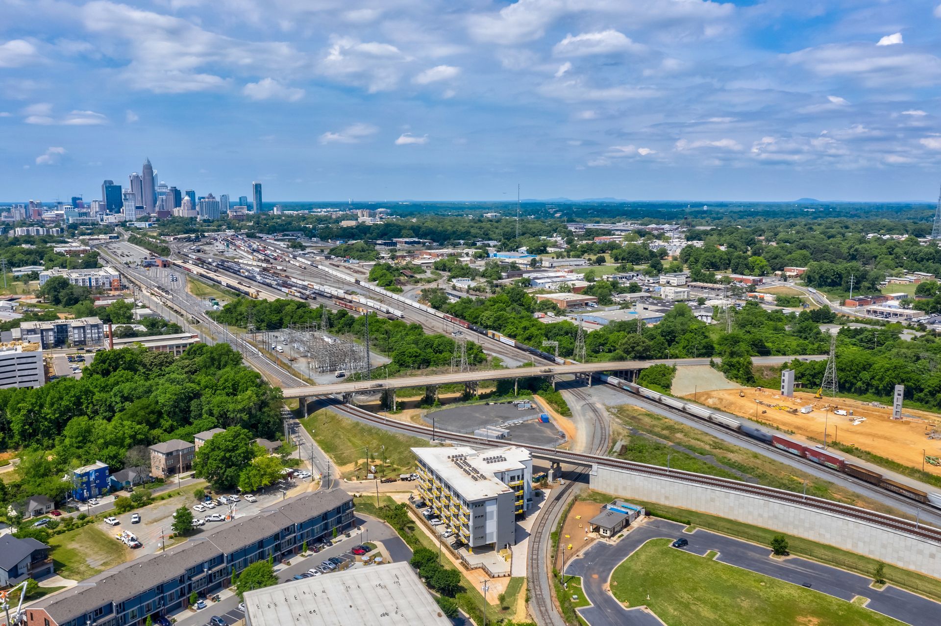 Aerial view of Charlotte, NC, with highways, buildings, and skyline under a blue sky.