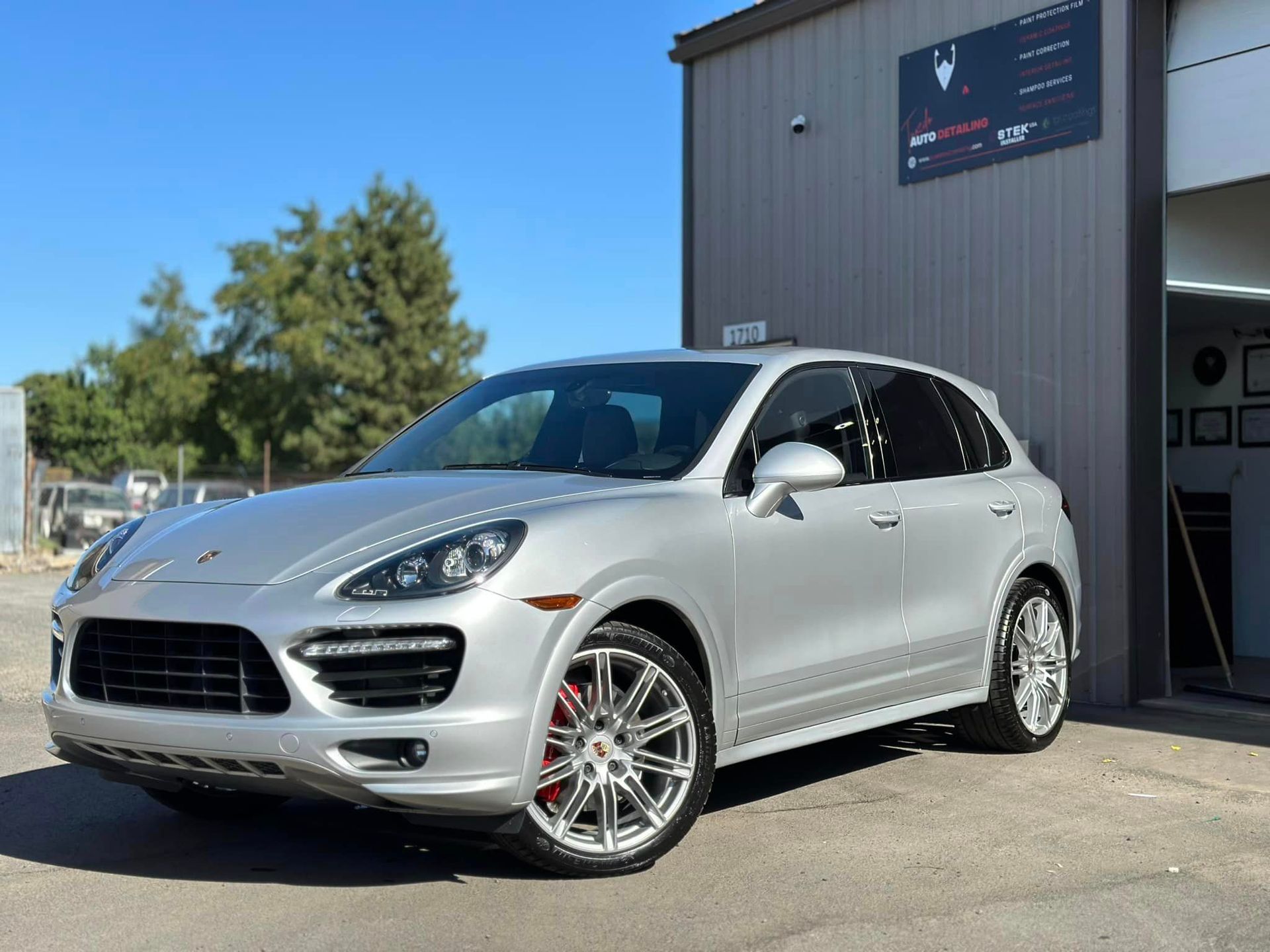 A silver porsche cayenne turbo is parked in front of a building.