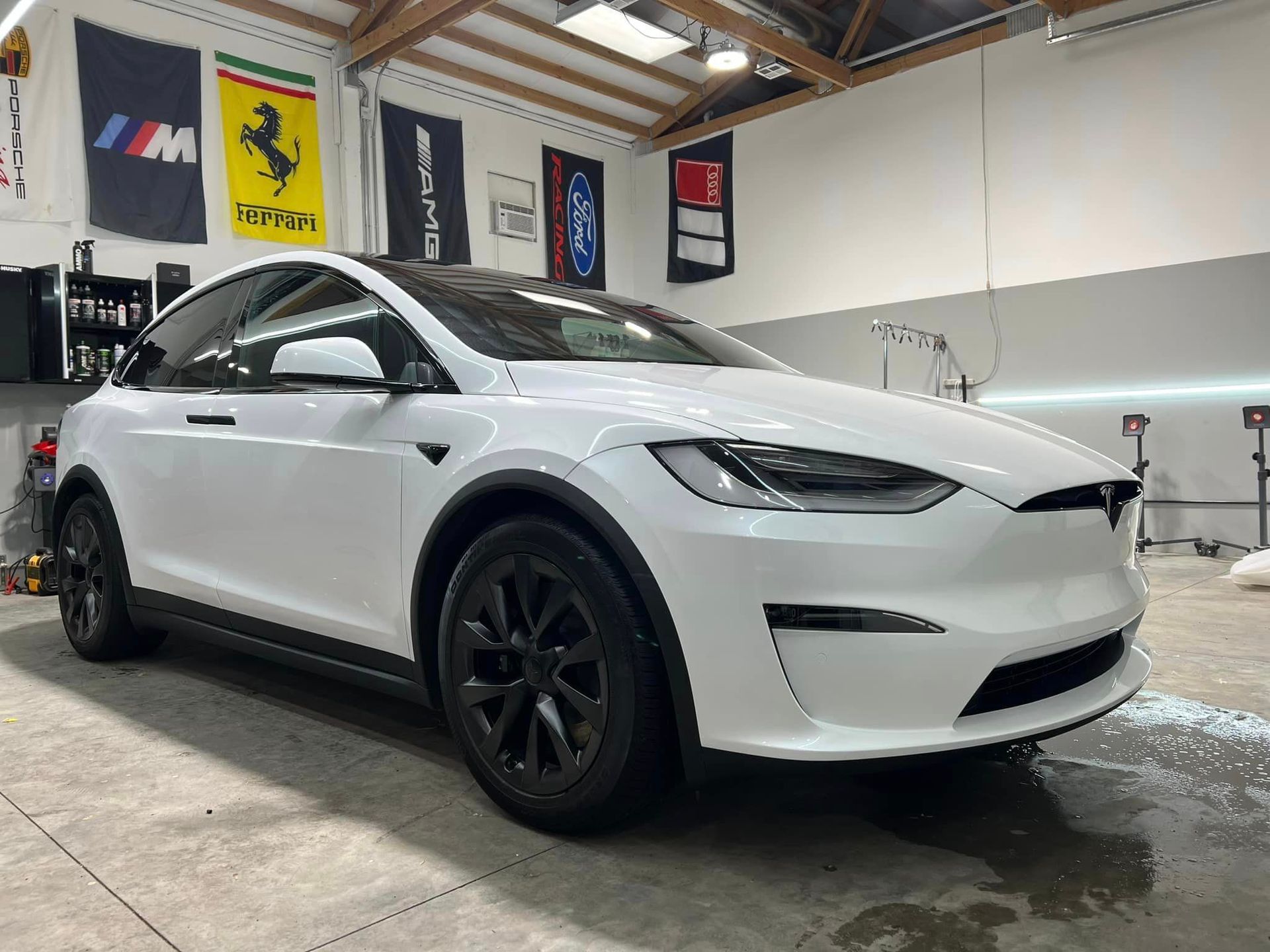 A white tesla model x is parked in a garage.