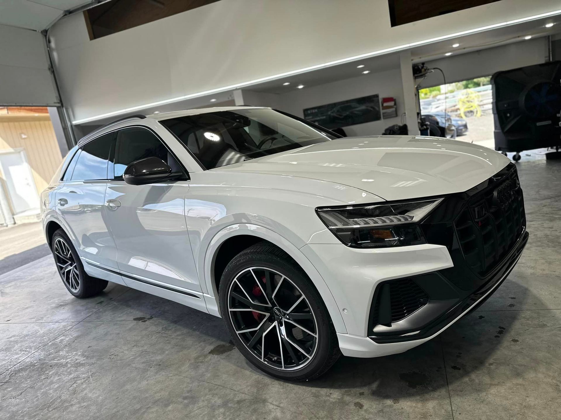 A white audi q8 is parked in a garage.