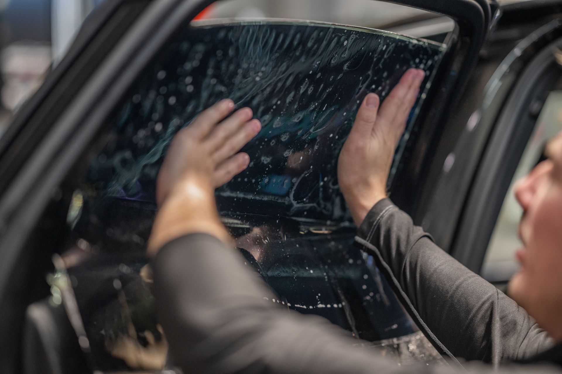 A person is applying tinted glass to a car window.