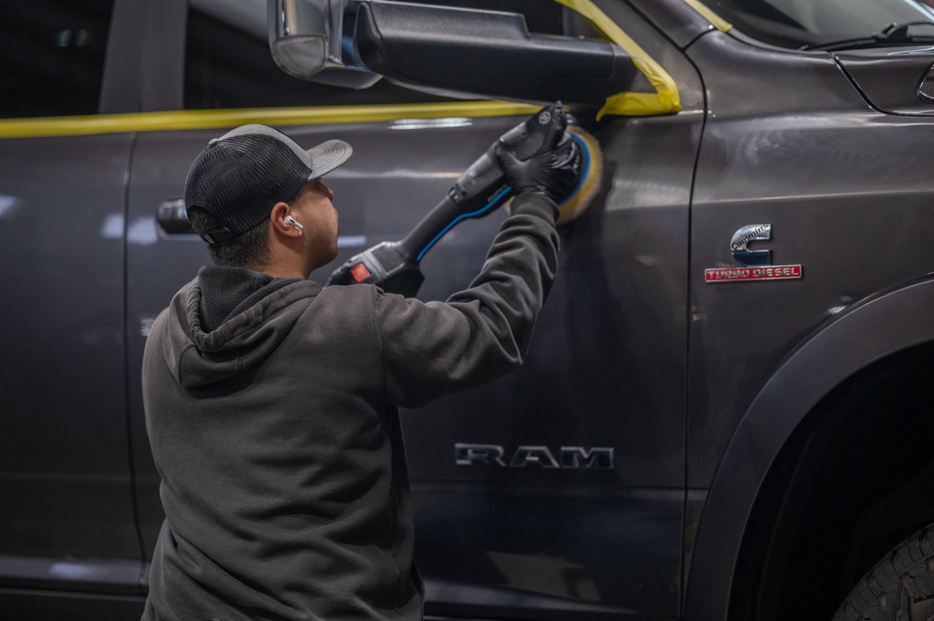 A blue car with black wheels and tires is parked in a parking lot.