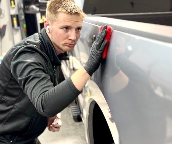 A man is cleaning the side of a truck with a sponge.
