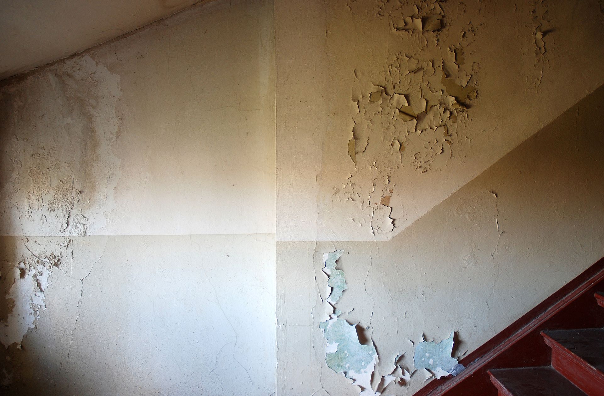 A staircase with peeling paint on the wall.