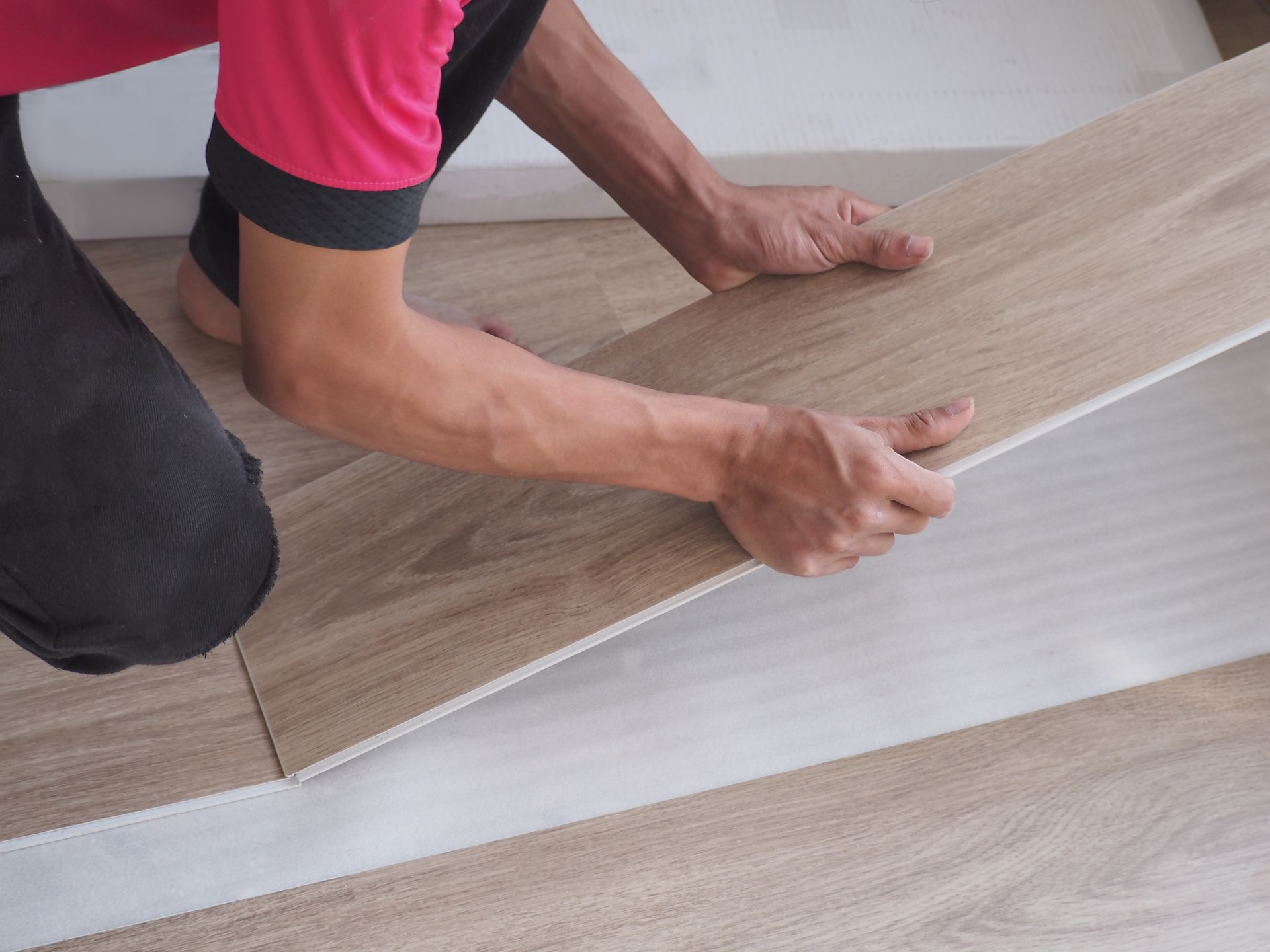 A man is installing a wooden floor in a room.