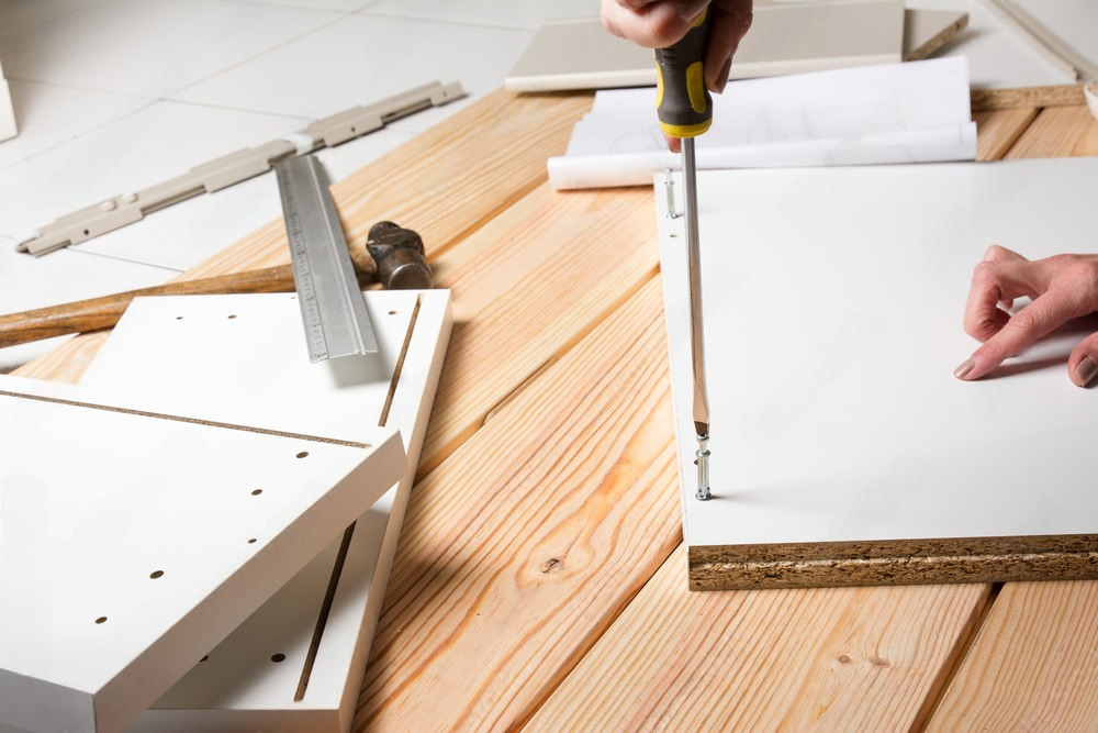 A person is using a screwdriver to screw a piece of wood.
