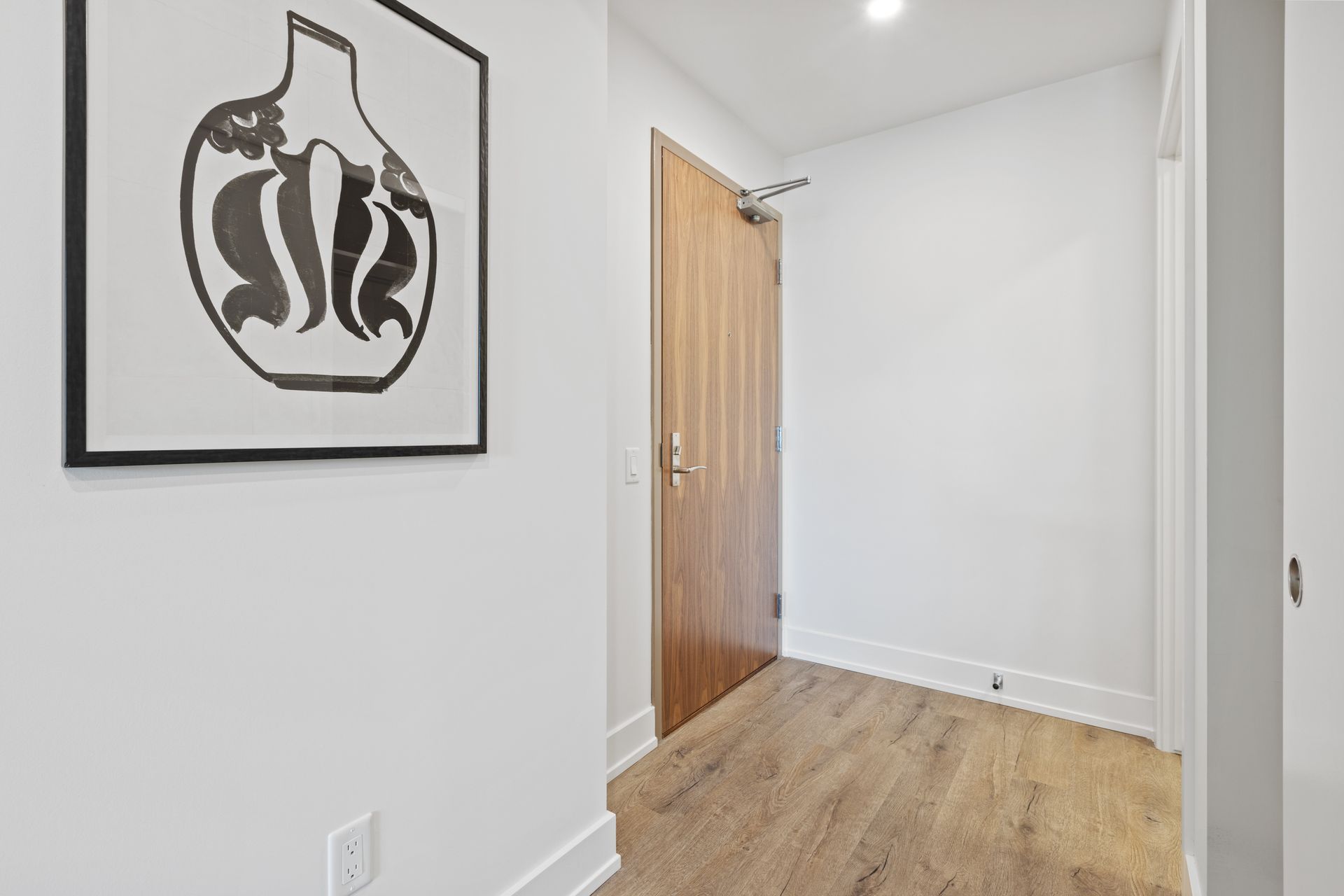 A hallway with a picture on the wall and a door.