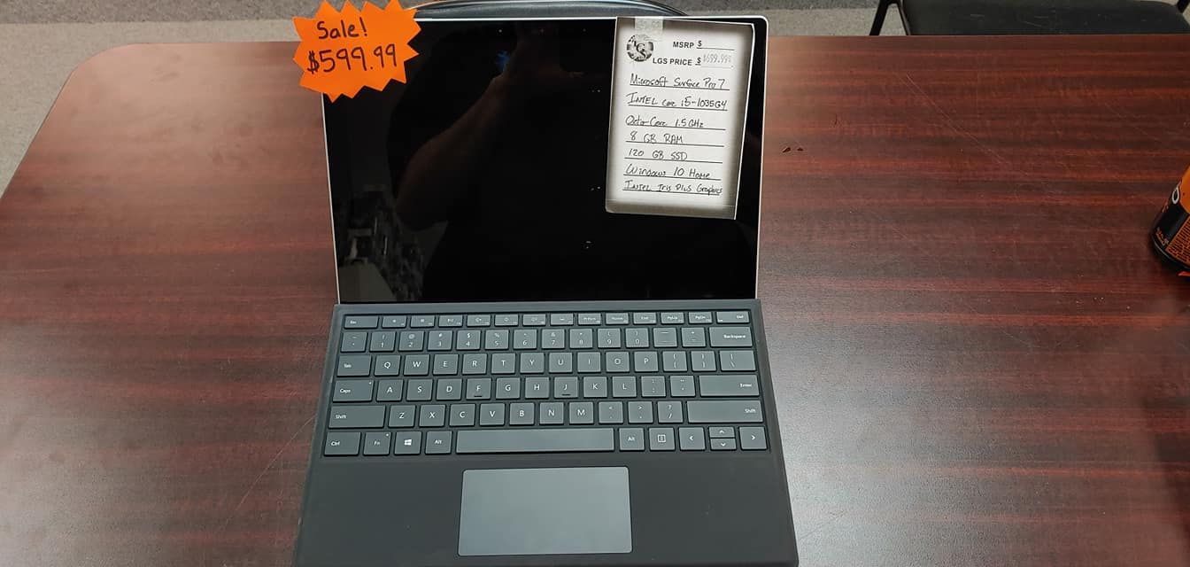 Laptop with attached keyboard and price tag on a wooden surface.