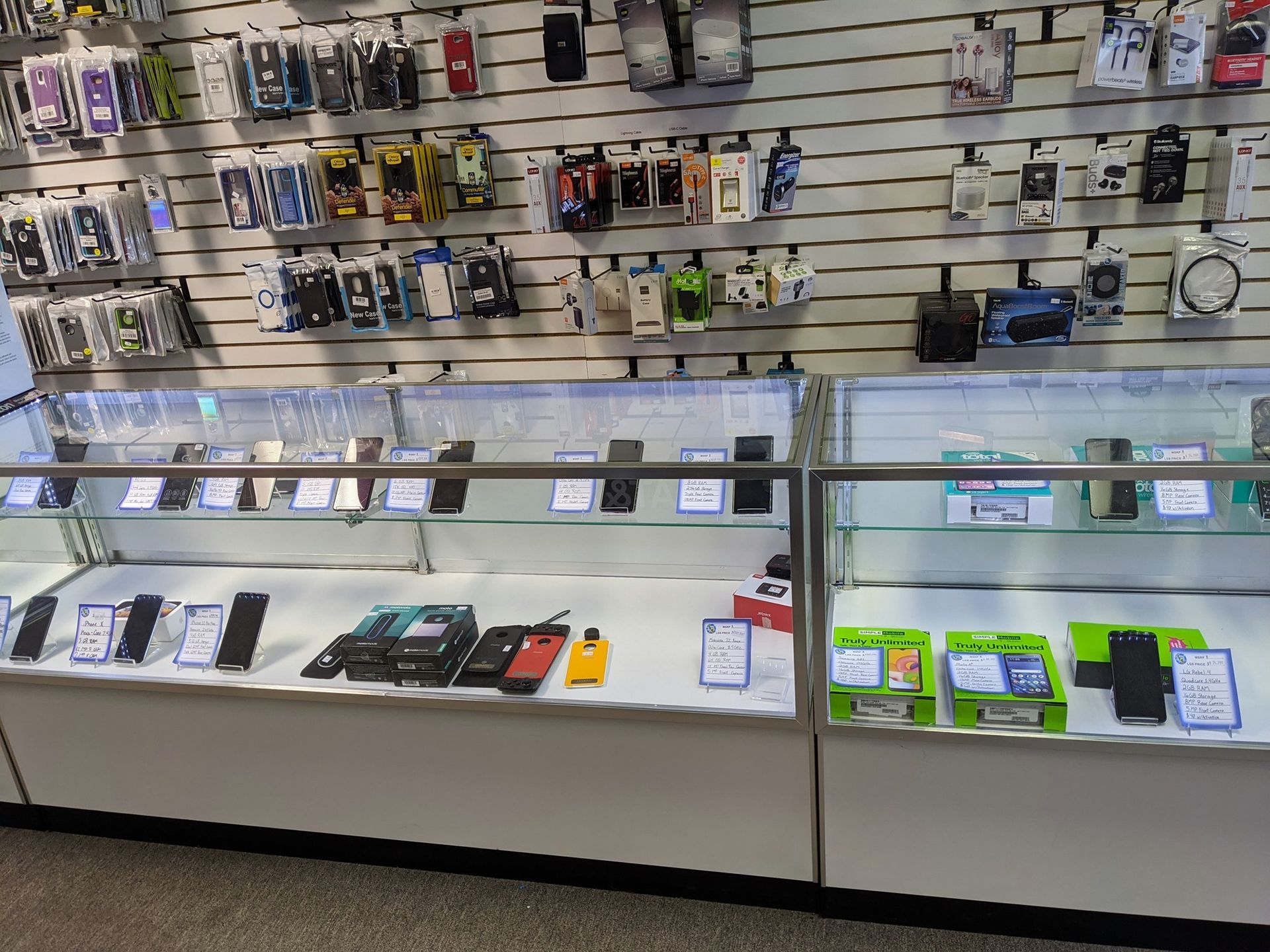 Cell phone store display with phones in glass cases and accessories on the wall.