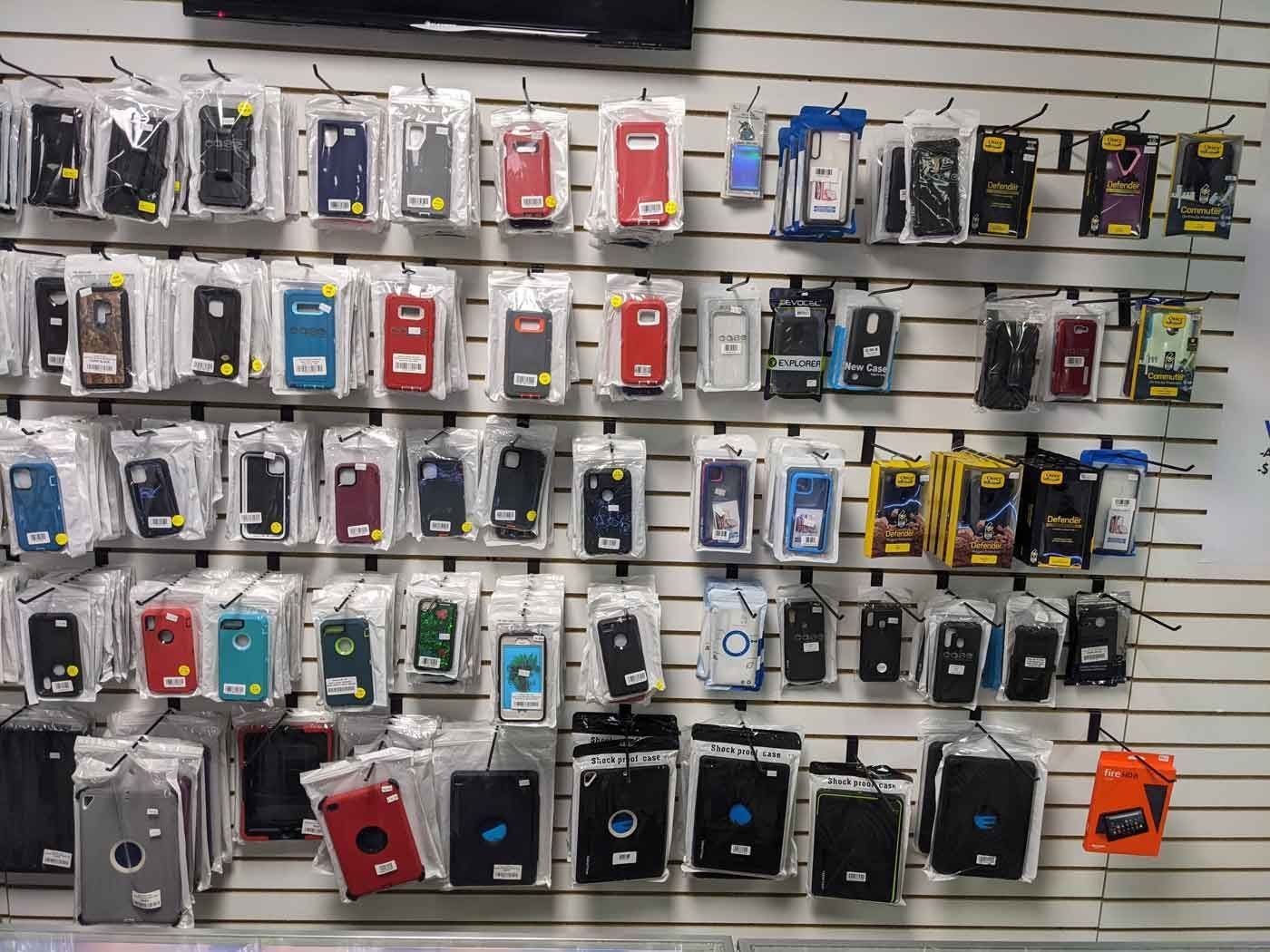 Wall display of various phone cases in clear plastic packaging.