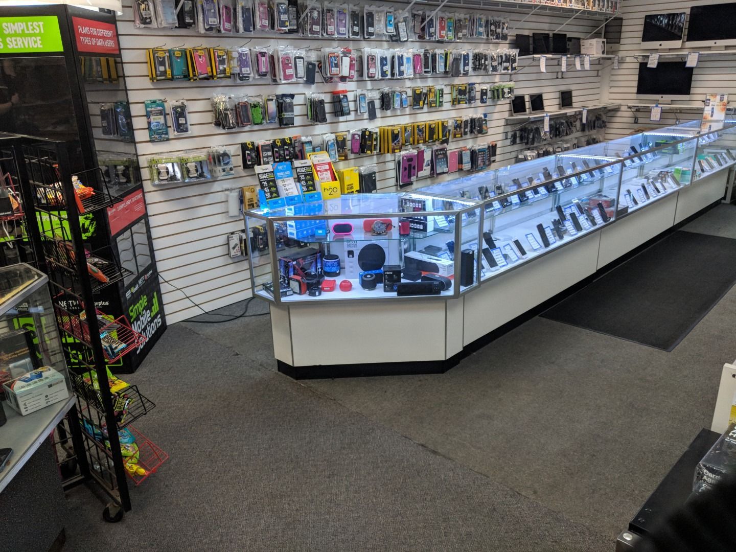Inside a cell phone store, display cases with phones, accessories on walls.