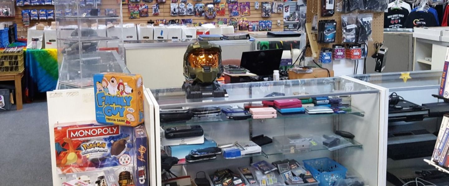 Interior of a store, gaming items for sale, glass display cases with Halo helmet on top.