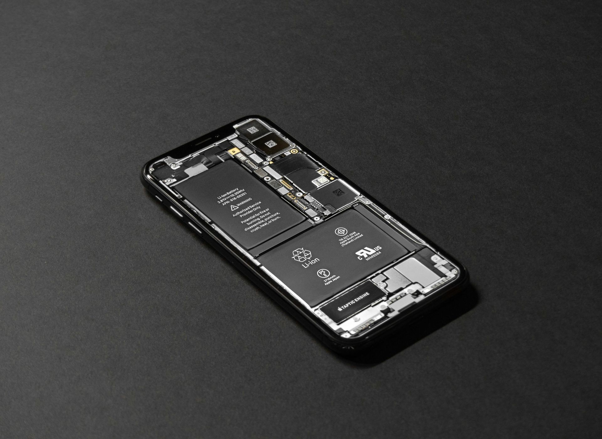 Smartphone with internal components exposed, on a black surface.